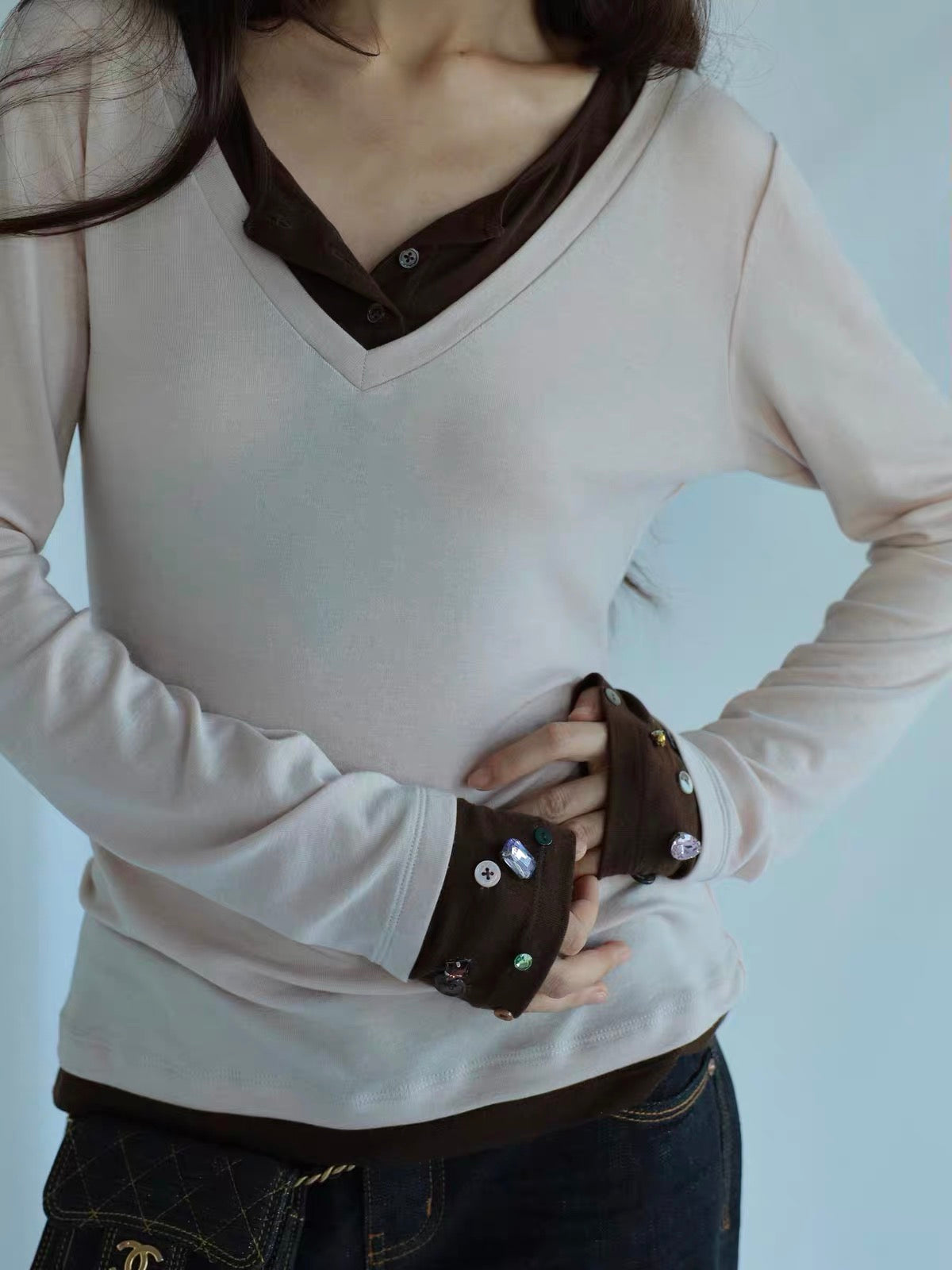 ジュエルボタン レイヤードニットトップス：青背景の服のアップ